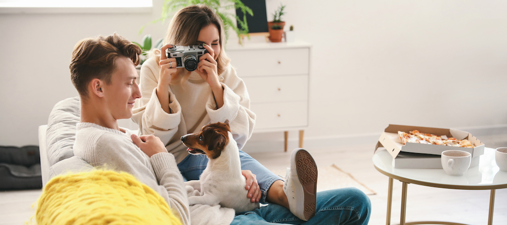 Couple sitting on couch in their vacation home taking picture of dog